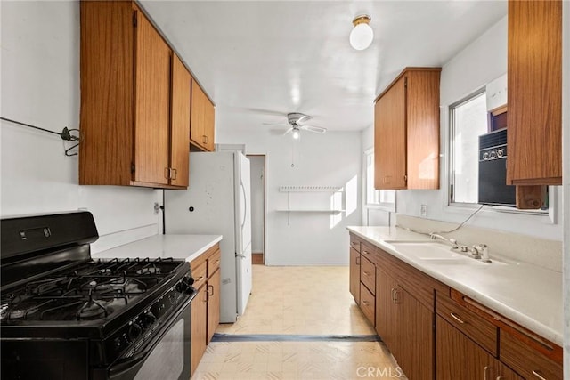 kitchen featuring light floors, light countertops, brown cabinets, gas stove, and a sink