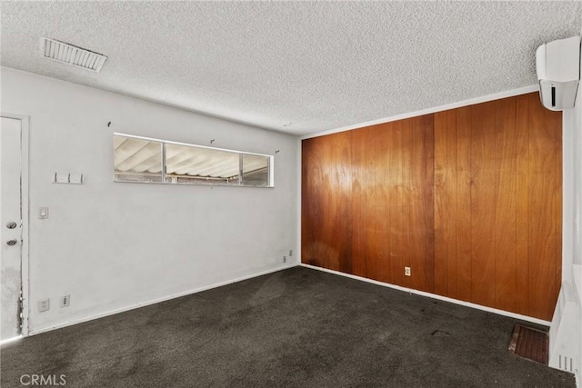 carpeted empty room with a wall mounted AC, visible vents, and a textured ceiling