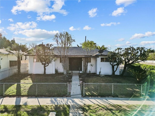 ranch-style home with a front lawn, a gate, a fenced front yard, and stucco siding