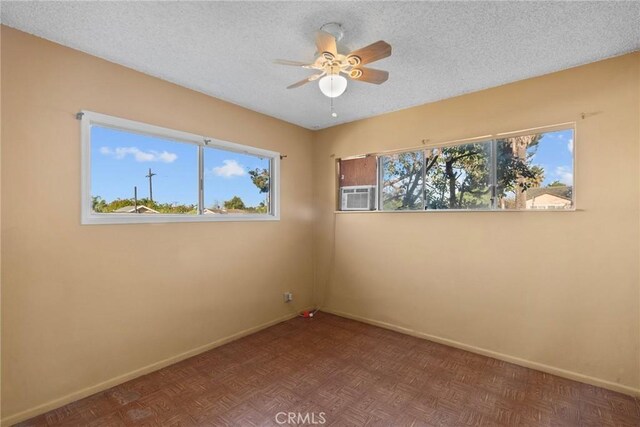 unfurnished room with a healthy amount of sunlight, a textured ceiling, and baseboards