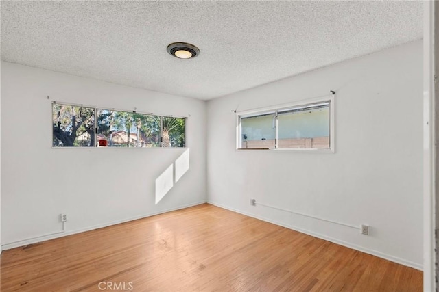 unfurnished room featuring baseboards, a textured ceiling, and wood finished floors