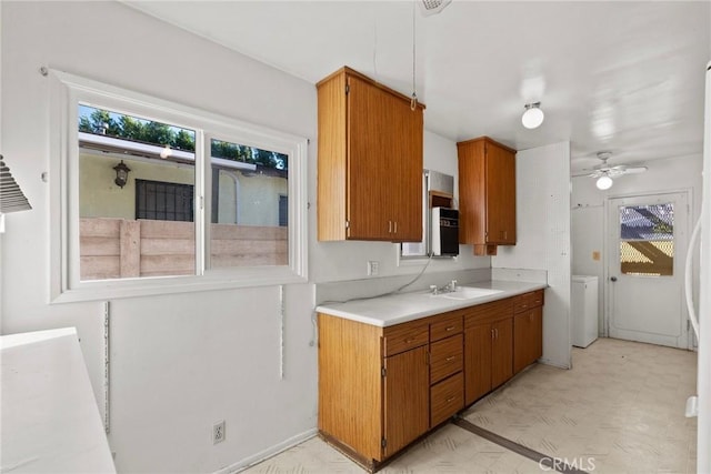 kitchen with brown cabinets, a sink, light countertops, light floors, and ceiling fan