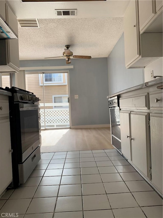 kitchen featuring ceiling fan, a textured ceiling, visible vents, and stainless steel gas stove