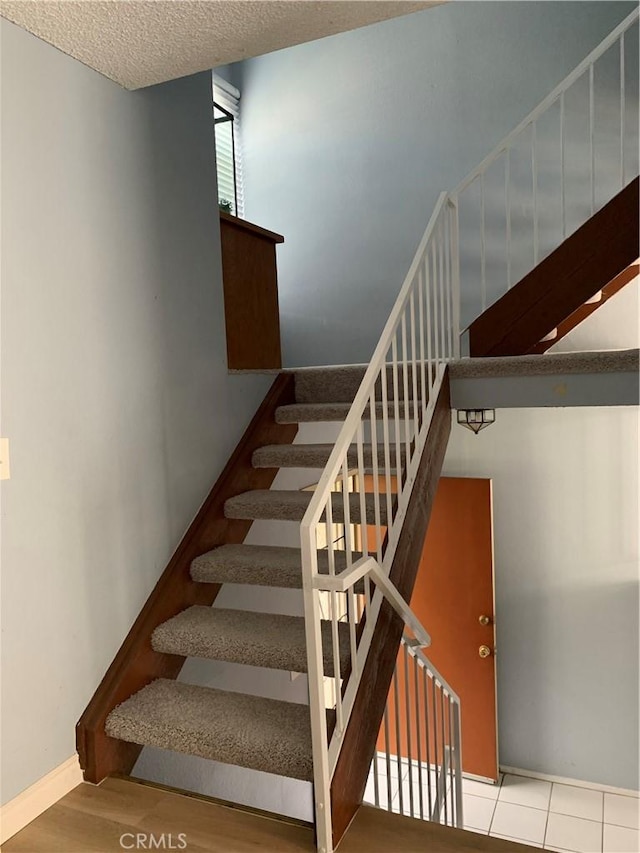 stairs featuring a textured ceiling and wood finished floors