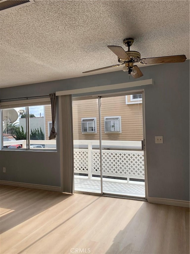 unfurnished room featuring a textured ceiling, baseboards, and wood finished floors