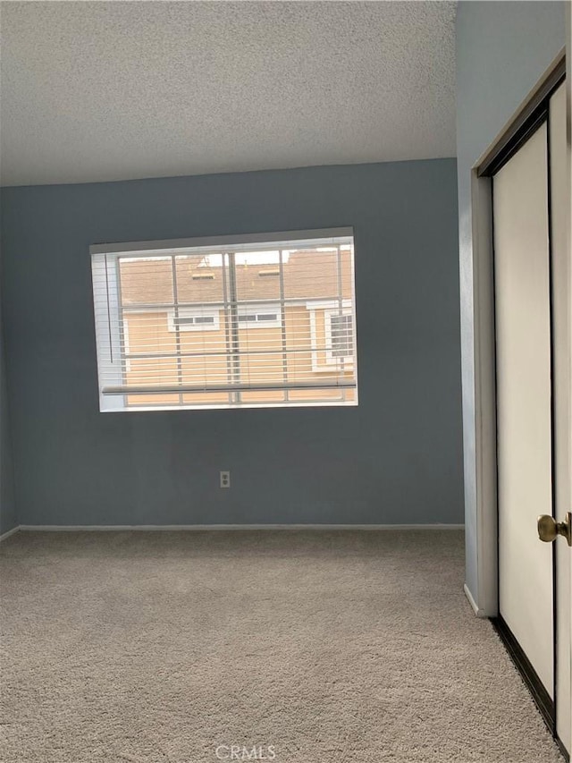 unfurnished bedroom with carpet, a closet, a textured ceiling, and baseboards