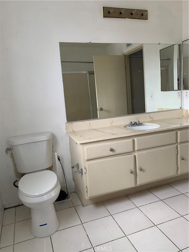 bathroom featuring toilet, a shower with shower door, vanity, and tile patterned floors