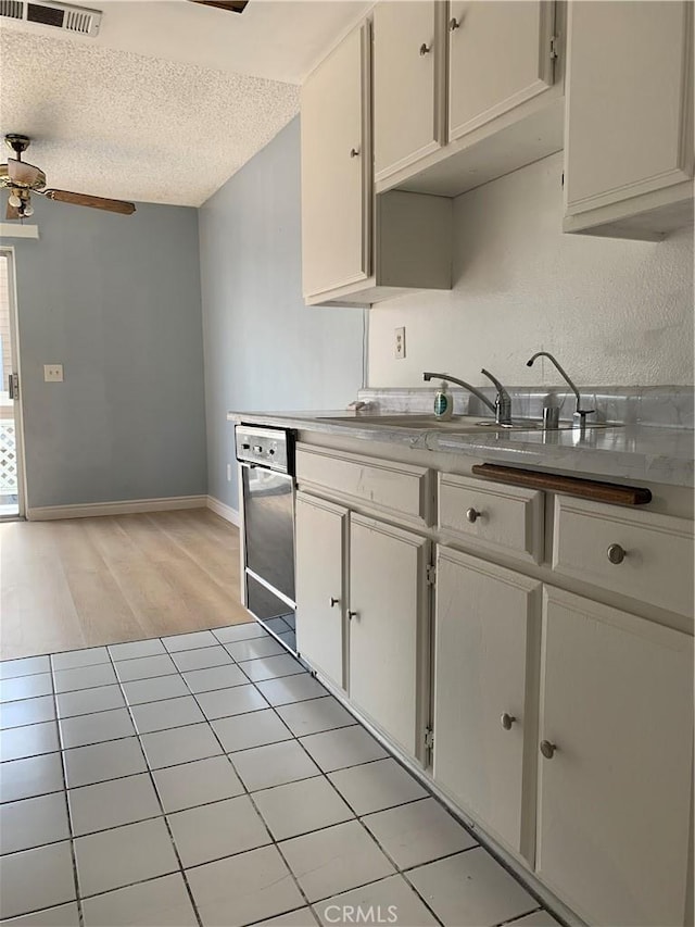 kitchen featuring baseboards, dishwasher, ceiling fan, a textured ceiling, and light wood-style floors