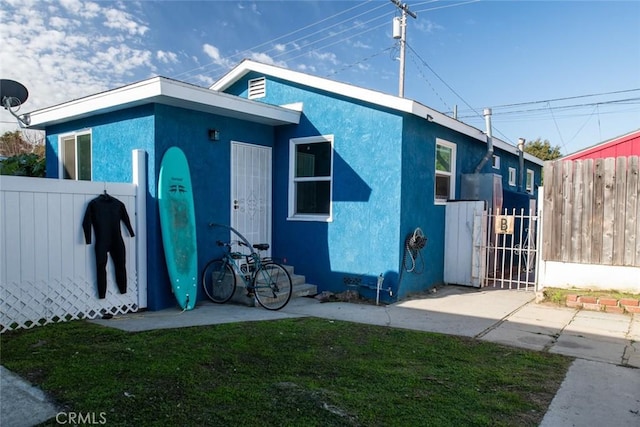 view of side of property with fence, a gate, and stucco siding