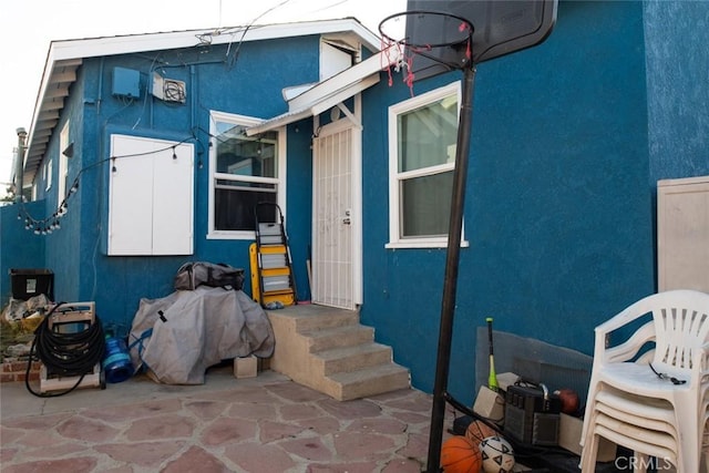 view of exterior entry featuring a patio area and stucco siding