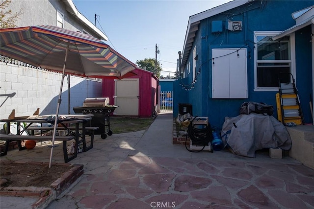 view of patio featuring an outdoor structure, area for grilling, fence, and a storage shed