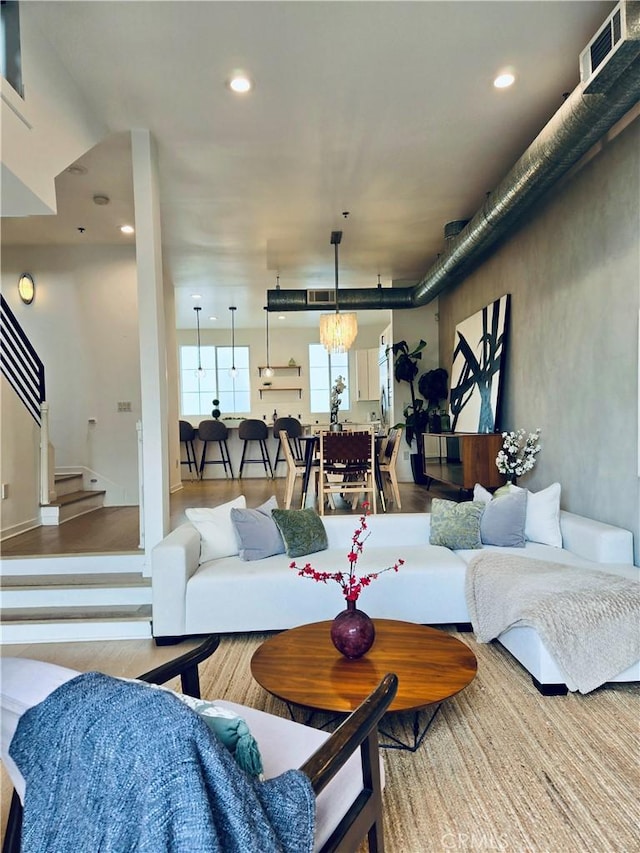 living area with stairs, wood finished floors, visible vents, and recessed lighting