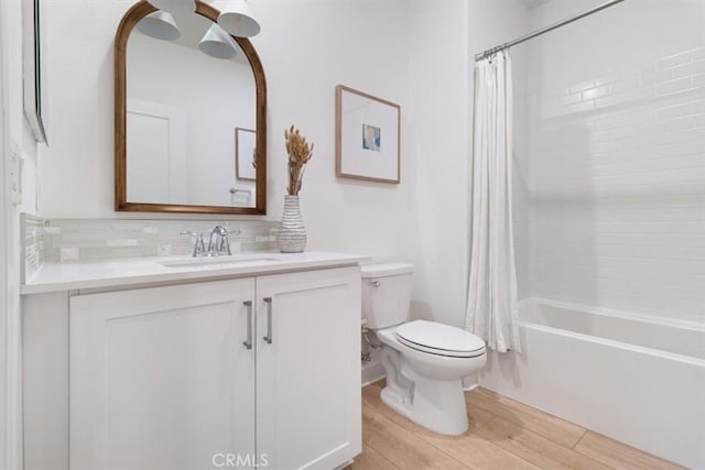 bathroom featuring toilet, decorative backsplash, shower / tub combo, wood finished floors, and vanity