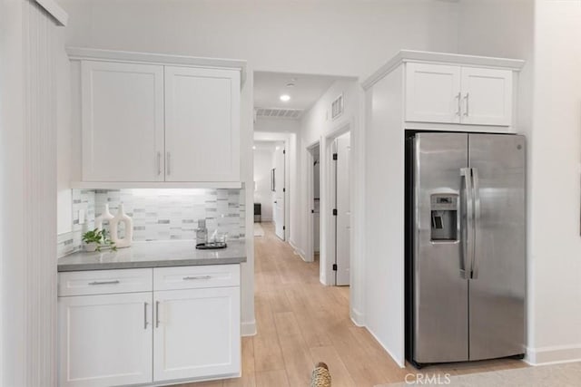 kitchen with decorative backsplash, white cabinets, stainless steel refrigerator with ice dispenser, and light wood finished floors