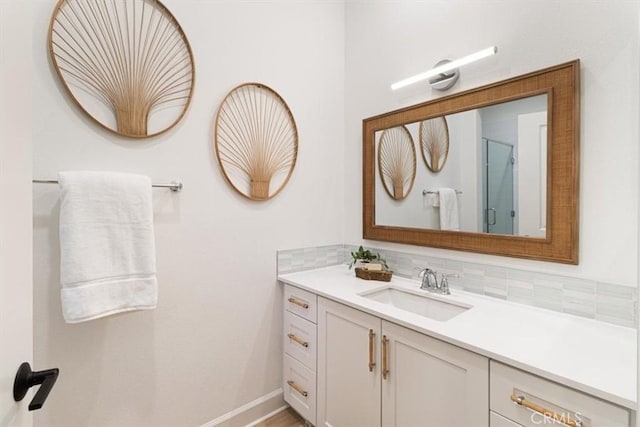 bathroom featuring decorative backsplash, baseboards, a stall shower, and vanity