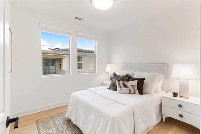 bedroom with baseboards, visible vents, and light wood-type flooring