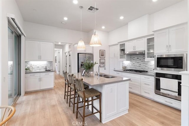 kitchen with visible vents, a kitchen bar, appliances with stainless steel finishes, light wood-style floors, and a sink