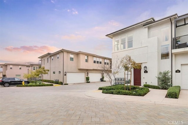 townhome / multi-family property with stucco siding, driveway, and an attached garage