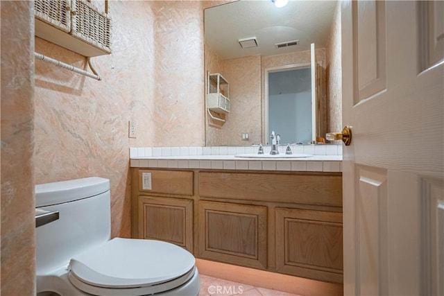 half bath featuring toilet, visible vents, and vanity