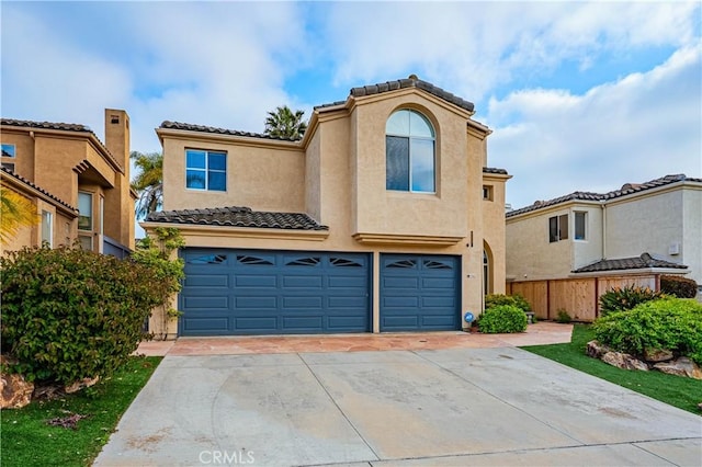 mediterranean / spanish house featuring fence, an attached garage, stucco siding, concrete driveway, and a tiled roof