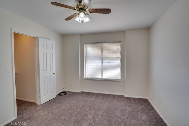 carpeted empty room featuring a ceiling fan and baseboards