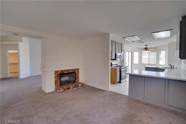 living area with light carpet, a brick fireplace, and a ceiling fan