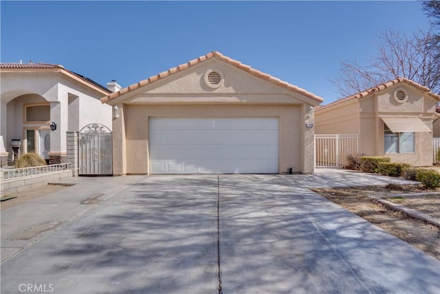 view of front of house featuring concrete driveway, a tile roof, an attached garage, a gate, and stucco siding