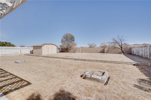 view of yard with a storage shed, an outdoor fire pit, an outdoor structure, and a fenced backyard