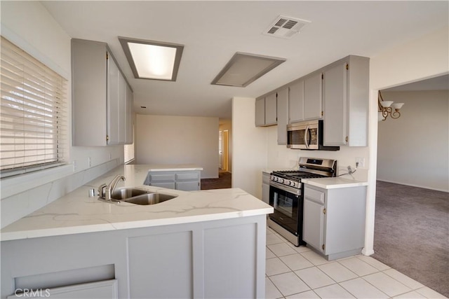 kitchen featuring stainless steel appliances, a sink, visible vents, and gray cabinetry