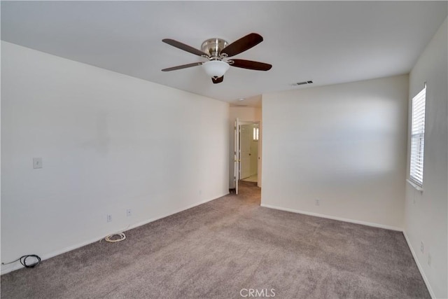 carpeted empty room with visible vents, ceiling fan, and baseboards