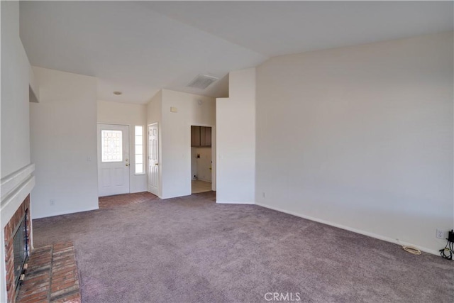 unfurnished living room with carpet floors, a fireplace, visible vents, and vaulted ceiling