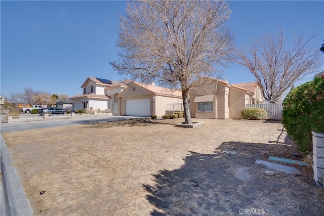 view of front of property with a garage, driveway, fence, and stucco siding