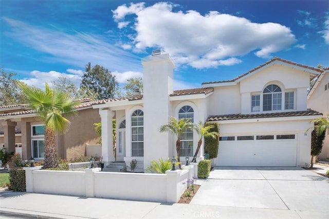 mediterranean / spanish-style house with concrete driveway, a fenced front yard, a chimney, an attached garage, and stucco siding