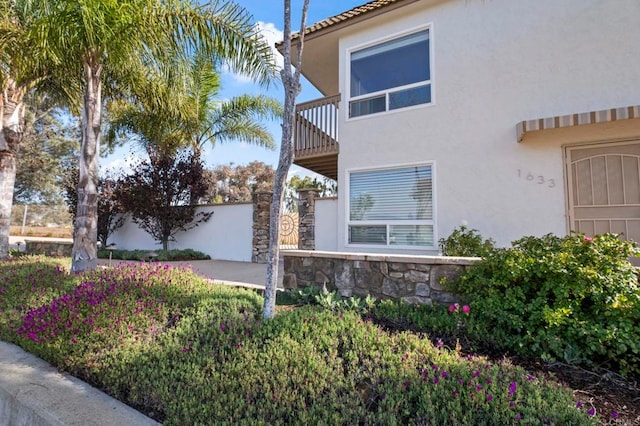 view of property exterior with a balcony, stone siding, and stucco siding