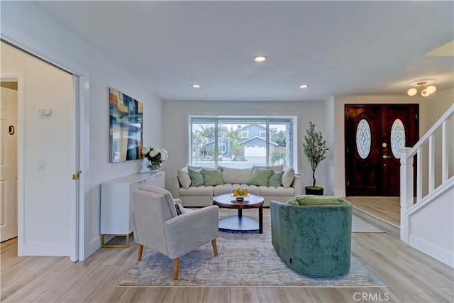 living area featuring light wood-type flooring, stairs, baseboards, and recessed lighting