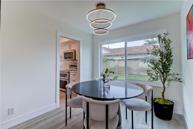 dining room with an inviting chandelier, light wood-style flooring, and baseboards