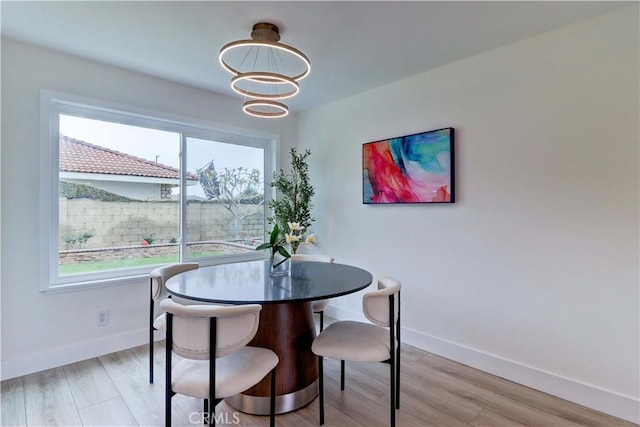 dining area featuring a healthy amount of sunlight, baseboards, a chandelier, and light wood-style flooring