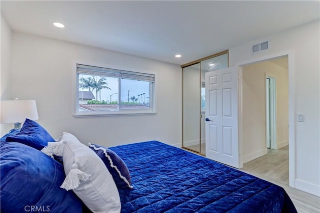 bedroom with recessed lighting, a closet, visible vents, and wood finished floors