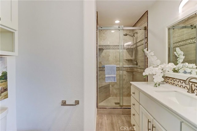 bathroom with a stall shower, recessed lighting, wood finished floors, and vanity