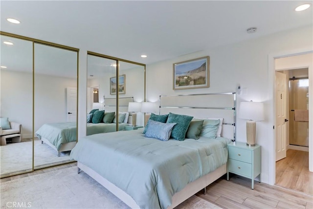 bedroom featuring recessed lighting, two closets, and wood finished floors