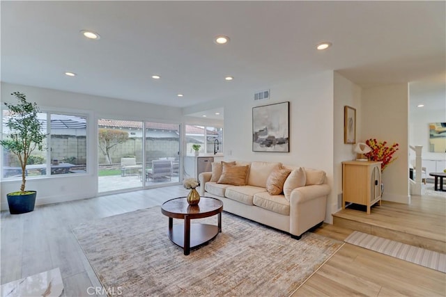 living room with recessed lighting, visible vents, and wood finished floors