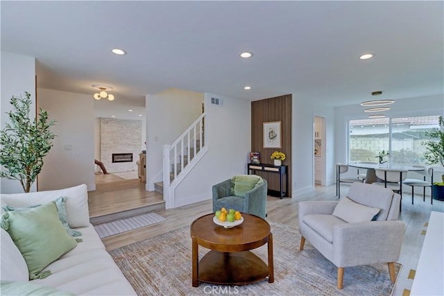 living room with recessed lighting, a large fireplace, visible vents, and stairway