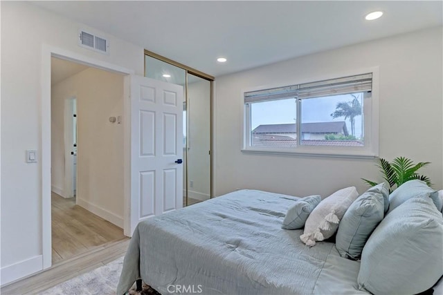 bedroom with light wood finished floors, recessed lighting, a closet, visible vents, and baseboards