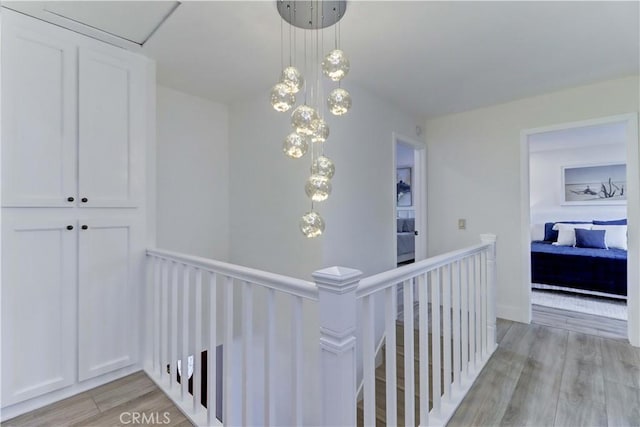 hall with light wood-type flooring and an upstairs landing