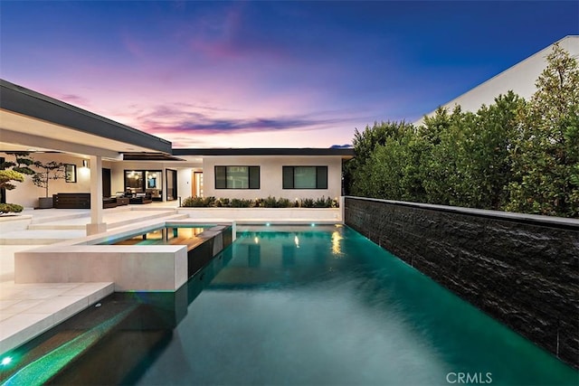 pool at dusk featuring an outdoor pool, a hot tub, an outdoor hangout area, and a patio