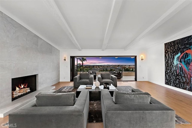 living area featuring baseboards, a fireplace, beamed ceiling, and wood finished floors