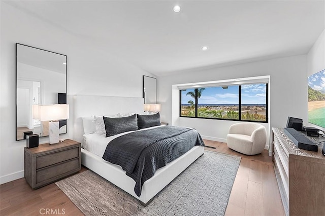 bedroom with lofted ceiling, light wood finished floors, baseboards, and recessed lighting
