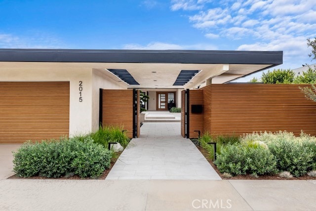 view of exterior entry with an attached garage and stucco siding