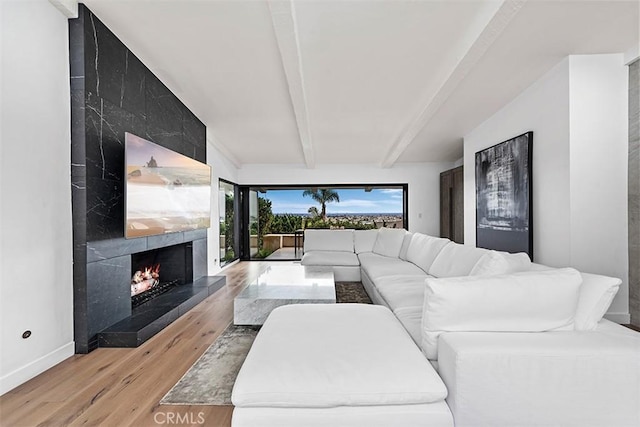living room featuring a premium fireplace, baseboards, beamed ceiling, and wood finished floors