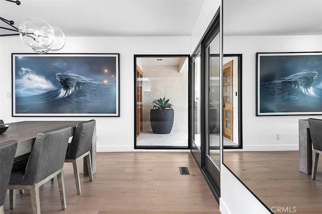 interior space with baseboards, visible vents, an inviting chandelier, and wood finished floors
